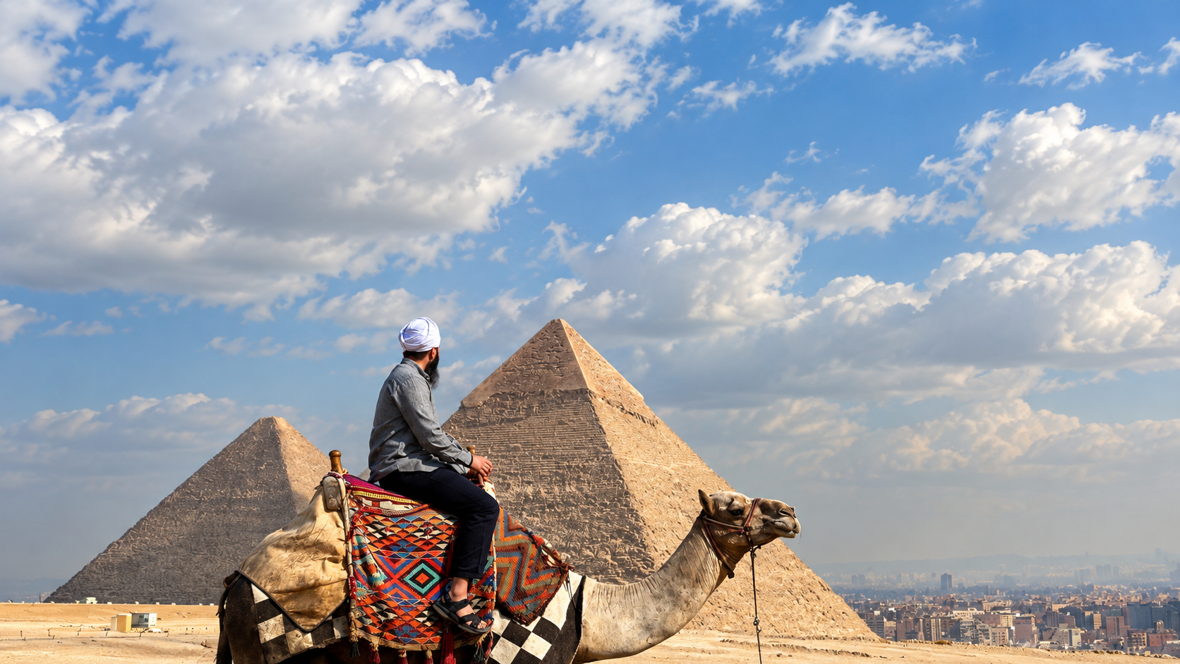 Camel rider in front of the Giza pyramids beneath a blue sky